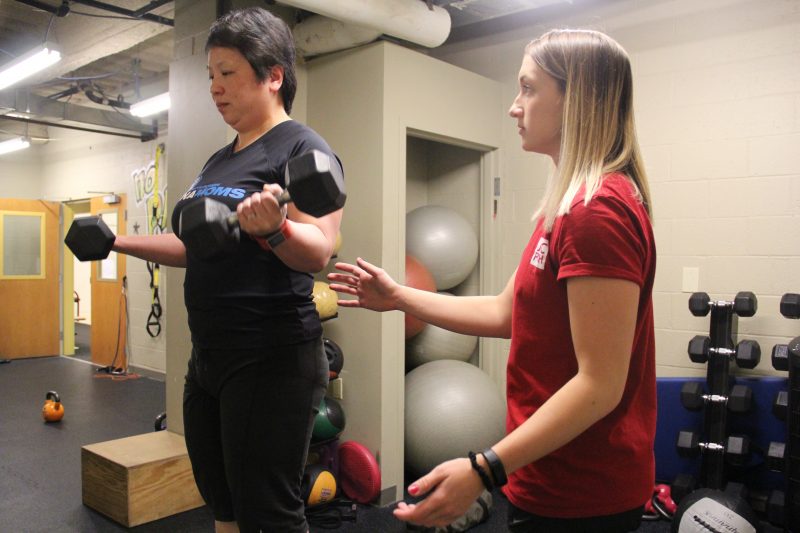 Women lifting weights with her physical therapist