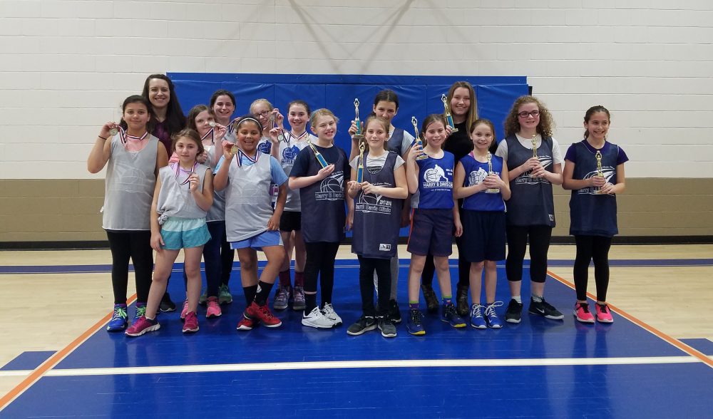 Basketball team posing with their trophies