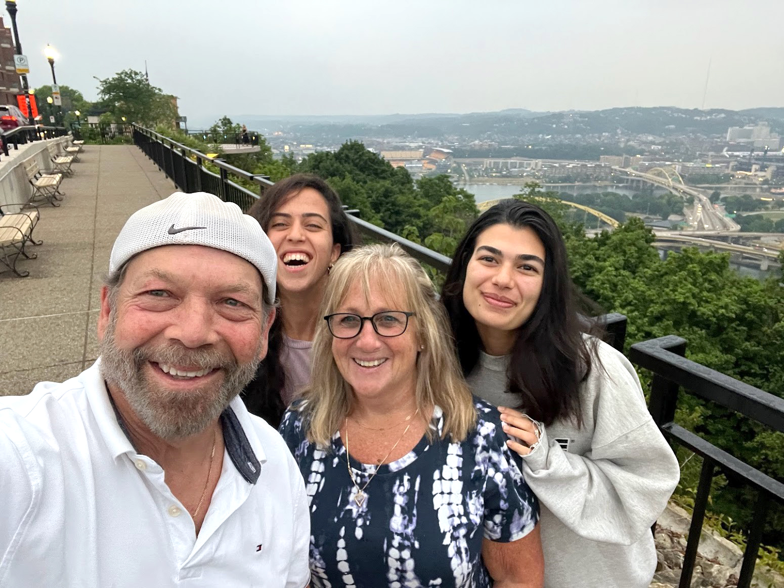 A selfie of a family, who is hosting a Shilchim, on top of Mount Washington with the Northside in the background.